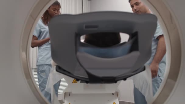 Slowmo snímek multietnických radiologů provádějících CT sken pacienta v nemocnici - Záběry, video