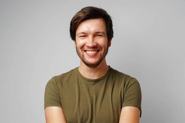 Handsome young man portrait smiling against grey background - Foto, Imagen