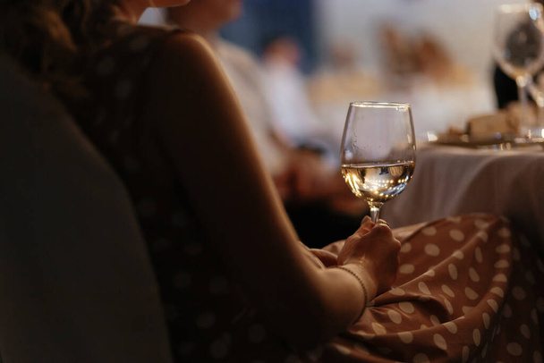 Ανέκφραστη γυναίκα που κρατάει ποτήρι κρασιού στο χέρι της. Θολή φόντο για το κείμενό σας. Υψηλής ποιότητας φωτογραφία - Φωτογραφία, εικόνα