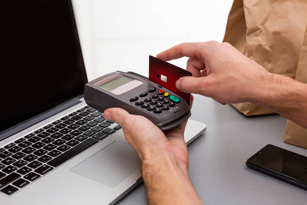 Manos masculinas con tarjeta de crédito en la máquina de tarjetas o terminal pos aislado sobre fondo blanco - Foto, imagen