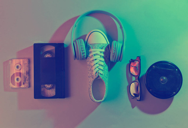 Audio, cassette vidéo, écouteurs, baskets, lunettes 3D. 80 ans. Onde rétro, néon, ultraviolet. Vue d'en haut, minimalisme - Photo, image