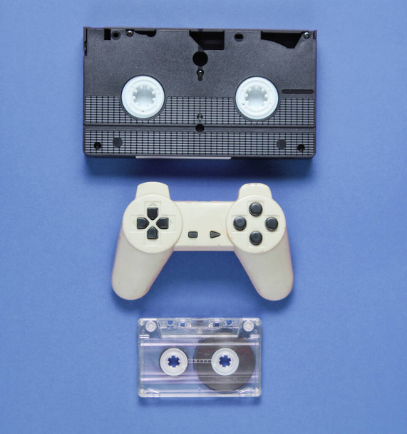 Pop culture attributes. audio cassette, retro gamepad, video tape on blue background. - Photo, Image
