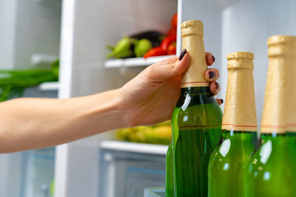 Female hand taking bottle of beer from a fridge - Foto, Imagem