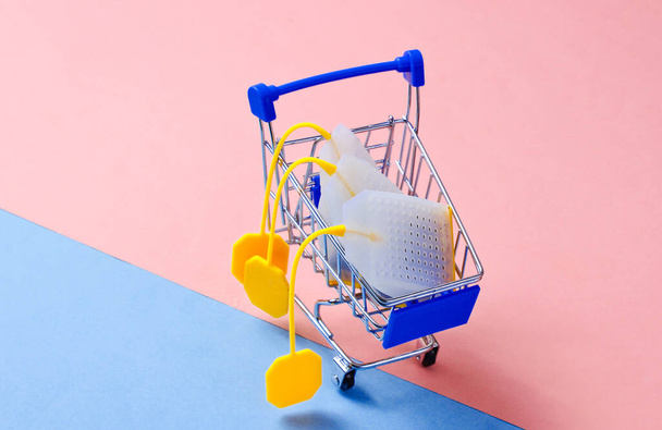 Bolsas de té en un carrito de compras de juguetes sobre un fondo pastel. Foto conceptual. - Foto, imagen