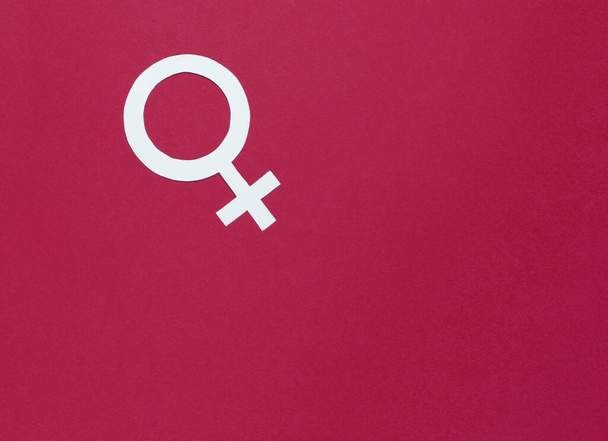 Símbolo de género femenino sobre fondo rojo. Vista superior. Minimalismo. Igualdad de género - Foto, imagen