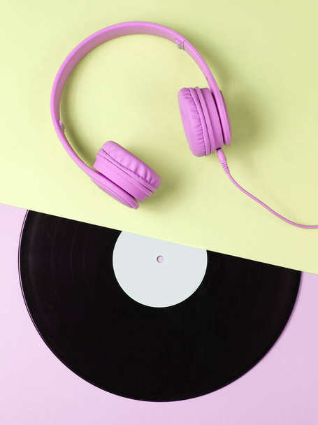 Retro 70s. Music lover. Headphones, lp record on green pink background. Flat lay. Top view. - Photo, Image