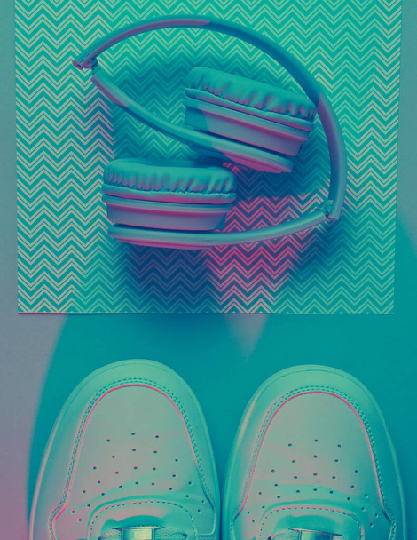 Sneakers e cuffie. Onda retrò, luce al neon, ultravioletto. Vista dall'alto, minimalismo - Foto, immagini