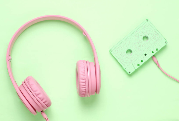 Headphones with audio cassette on green background. Retro style, minimalism. Flat lay. Top view. - Fotó, kép