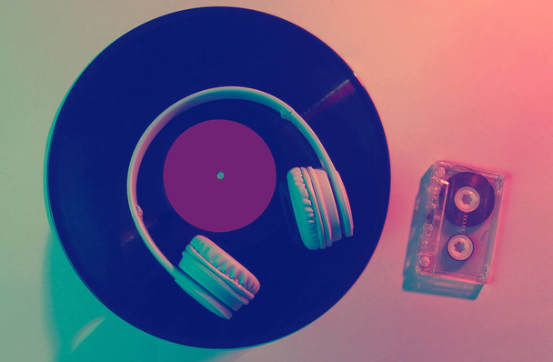 Casque avec cassette audio, disque vinyle. Onde rétro, néon bleu-rose, ultraviolet. Vue d'en haut, minimalisme - Photo, image