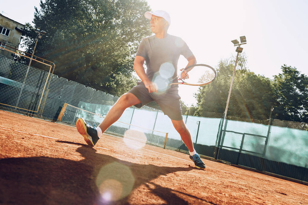 Middle-aged man playing tennis on outdoor tennis filed - Foto, Imagem