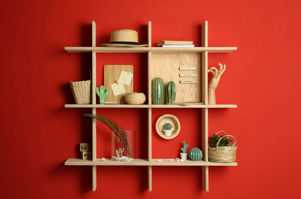 Stylish wooden shelves with decorative elements on red wall - Photo, Image