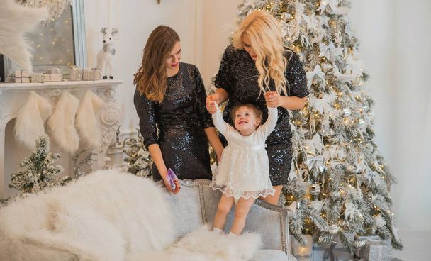 Christmas family scene, two women with a child, happy moms, New year time - Photo, Image