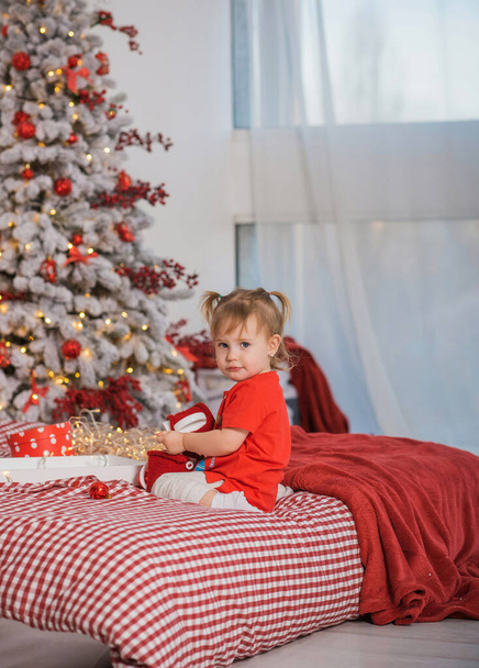 Winterferienkonzept. Inspiration und Märchenzeit. Kind in der Nähe des Weihnachtsbaums an Feiertagen. Ziemlich schöne gemütliche Urlaubstage, magische Weihnachtszeit - Foto, Bild