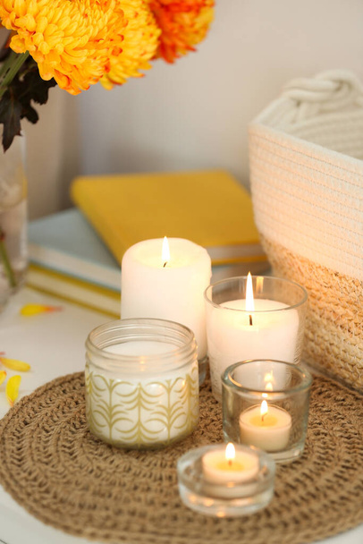 Beautiful burning candles, bag and flowers on table at home - Foto, afbeelding