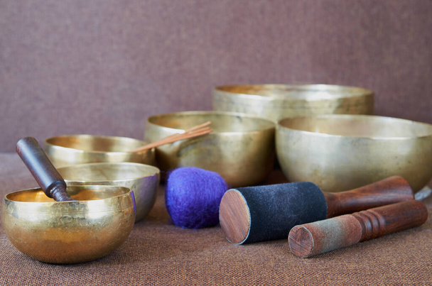 Tibetan singing bowls with sticks on the brown cloth background - music instruments for meditation, relaxation after yoga practice and healing massage - Photo, Image