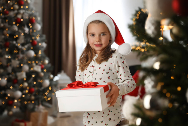 Menina bonito segurando caixa de presente no quarto decorado para o Natal - Foto, Imagem