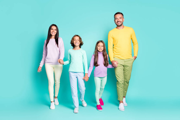 Photo portrait of full family walking forward holding hands isolated on vivid teal colored background - Fotó, kép