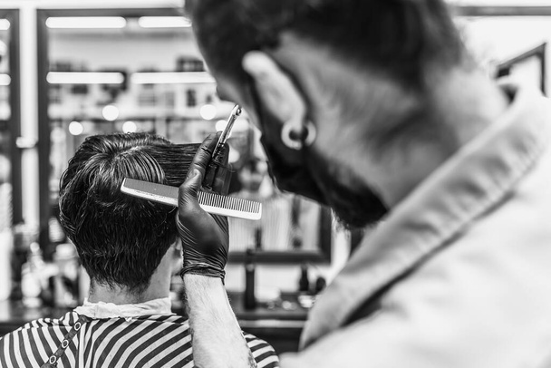 Barbier fait une coupe de cheveux et coiffure dans un salon de coiffure, salon de beauté.  - Photo, image