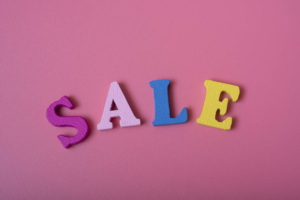 La venta de palabras sobre un fondo rosa de letras multicolores. concepto de ventas y descuentos. - Foto, Imagen