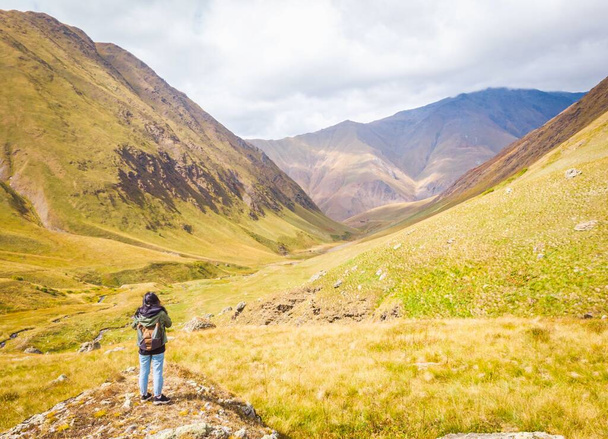 Mochilera mujer de pie en la roca con vistas panorámicas valle de Juta en las montañas del Cáucaso. Kazbegi viajar. Georgia - Foto, Imagen