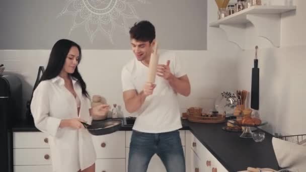 ενθουσιασμένοι χορό ζευγάρι με πλάστη και τηγάνι στην κουζίνα - Πλάνα, βίντεο