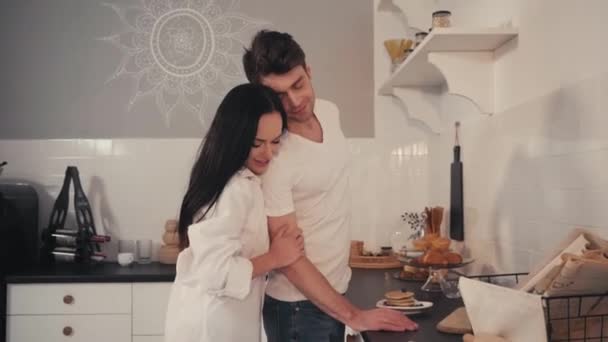 sensual woman seducing boyfriend standing near pancakes in kitchen - Footage, Video