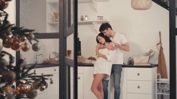 feliz joven pareja abrazando con los ojos cerrados en la cocina - Metraje, vídeo