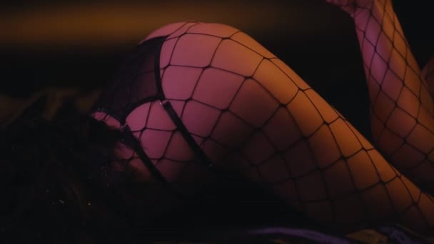 обрезанный вид сексуальной женщины в рыбных сетках колготки на черном диване - Кадры, видео