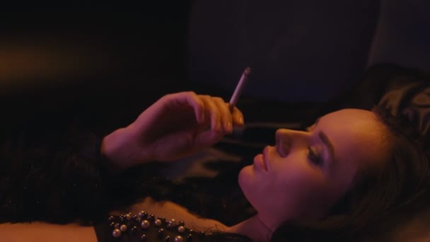 mladá brunetka žena v podprsenka kouření cigarety na černé  - Záběry, video