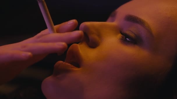 close-up van jonge brunette vrouw roken sigaret op zwart  - Video