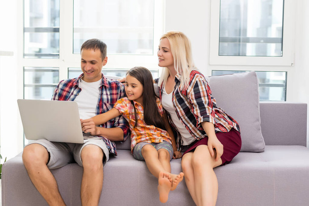 Glückliche Familie nutzt Laptop gemeinsam auf Sofa im Haus - Foto, Bild