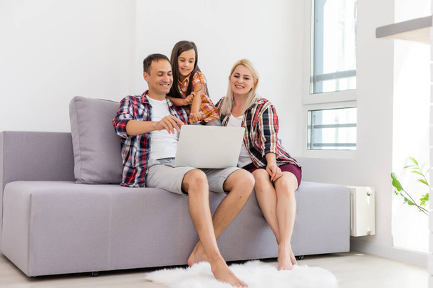 Familia feliz usando el ordenador portátil juntos en el sofá en casa - Foto, Imagen