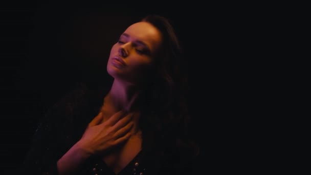 brunette vrouw in nep bont jas aanraken sexy lichaam geïsoleerd op zwart - Video