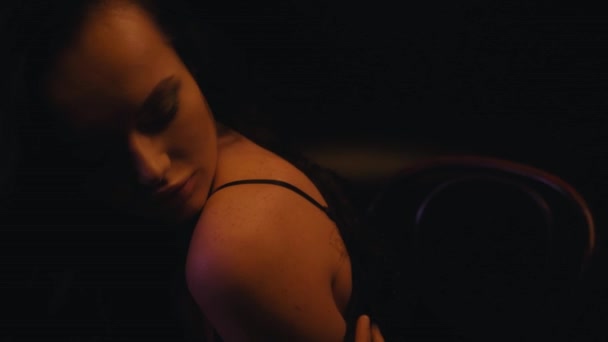 mujer sexy en sujetador y abrigo de piel sintética tocando el cuerpo en negro - Imágenes, Vídeo