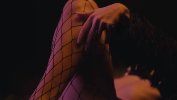 Gestellfokus der sexy Frau im Kunstpelzmantel berührt Körper auf Schwarz - Filmmaterial, Video