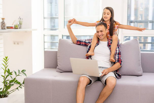 Glückliche Familie mit Kind nutzt Technologien, während sie zu Hause auf dem Sofa sitzt - Foto, Bild