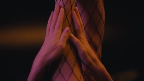 vista parziale della donna toccare gamba in calze a rete su nero  - Filmati, video