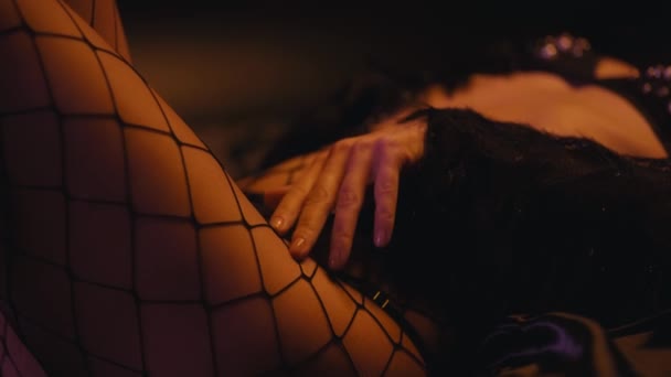 sexy donna in calze a rete sdraiato e toccante corpo su sfondo scuro - Filmati, video
