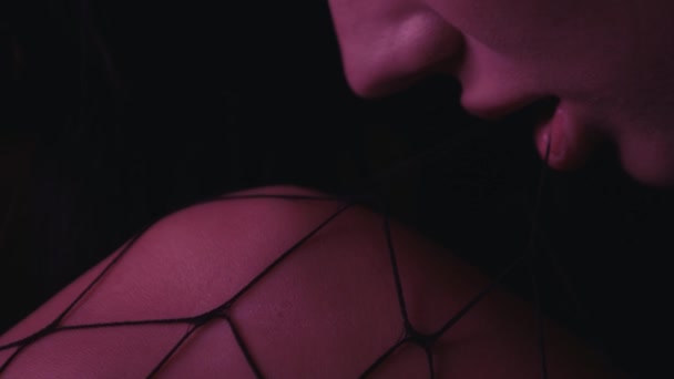 przycięty widok sexy kobieta gryzie kabaretki rajstopy izolowane na czarny - Materiał filmowy, wideo