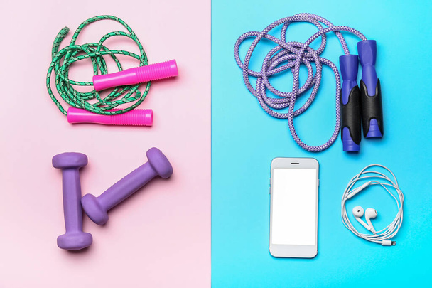 Комплект спортивного инвентаря и мобильного телефона на цветном фоне - Фото, изображение