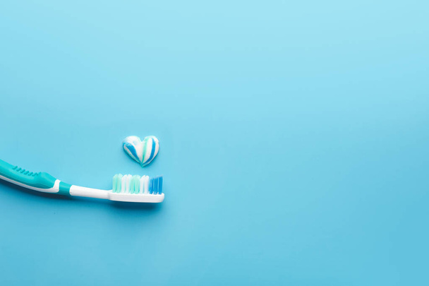 Cepillo de dientes y corazón de pasta sobre fondo de color - Foto, imagen