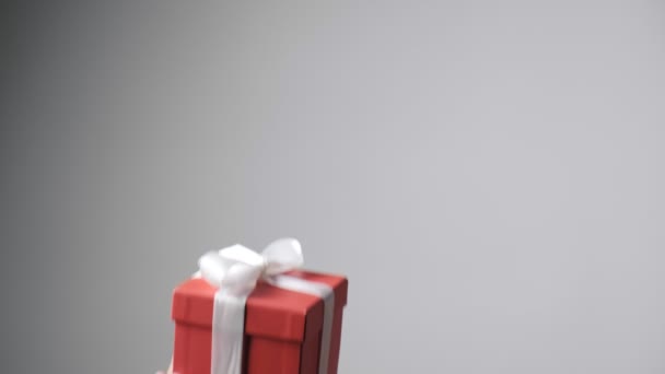 白いリボンで赤い箱を渡す子供たちの手。クリスマス、新年の驚き - 映像、動画