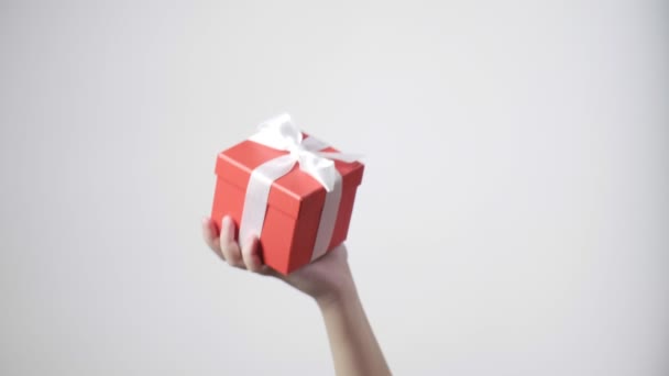 A gyerekek kézben tartják a piros ajándékot szalaggal. Karácsony, újév, születésnapi meglepetés - Felvétel, videó