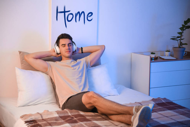 Young man listening to music in bedroom at home - Foto, Bild