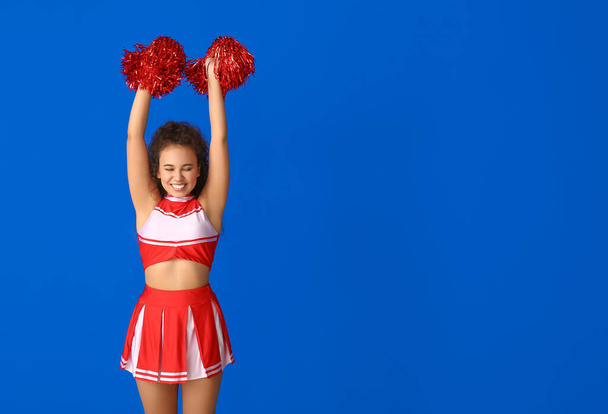 Beautiful young cheerleader on color background - Фото, изображение