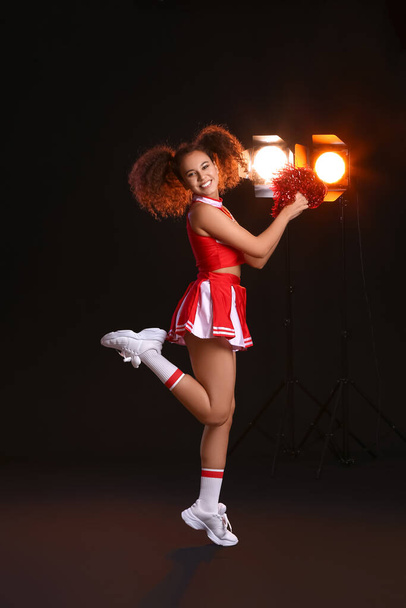 Piękna młoda cheerleaderka na ciemnym tle - Zdjęcie, obraz
