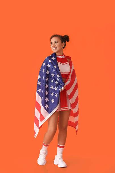Mooie jonge cheerleader met USA vlag op kleur achtergrond - Foto, afbeelding