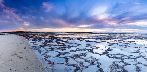 Ένα όμορφο πανόραμα ηλιοβασίλεμα πάνω από τον ωκεανό με βραχώδη παραλία και παλιρροϊκές πισίνες στο προσκήνιο - Φωτογραφία, εικόνα
