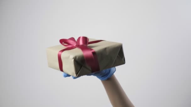 mão em luva protetora azul dá caixa de presente com fita. COVID-19 Natal - Filmagem, Vídeo