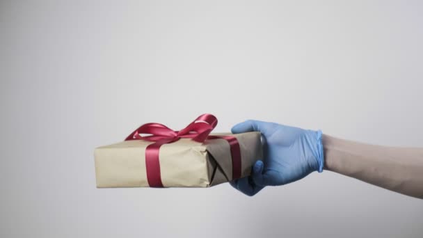 子供に赤いリボンでクリスマスの贈り物を与える青い保護手袋で手 - 映像、動画